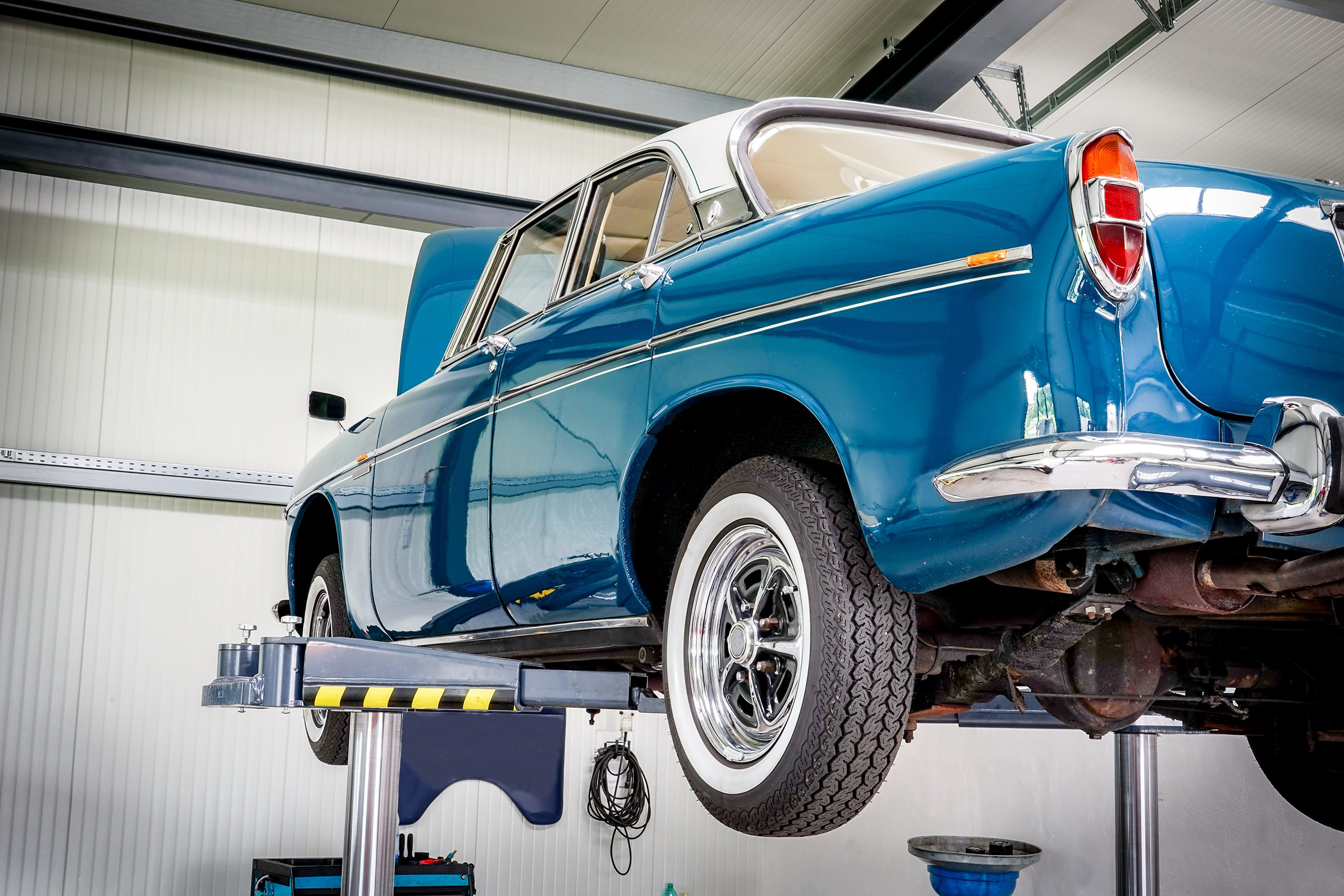 KFZ-Werkstatt, blauer Oldtimer auf einer Hebebühne KFZ-Werkstatt, blauer Oldtimer auf einer Hebebühne